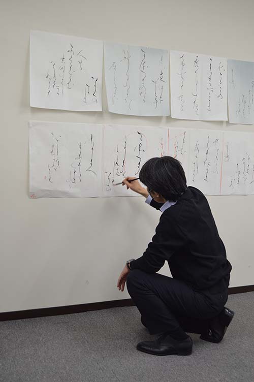 壁に貼ったお手本に日比野先生が朱筆でポイントを書き入れる
